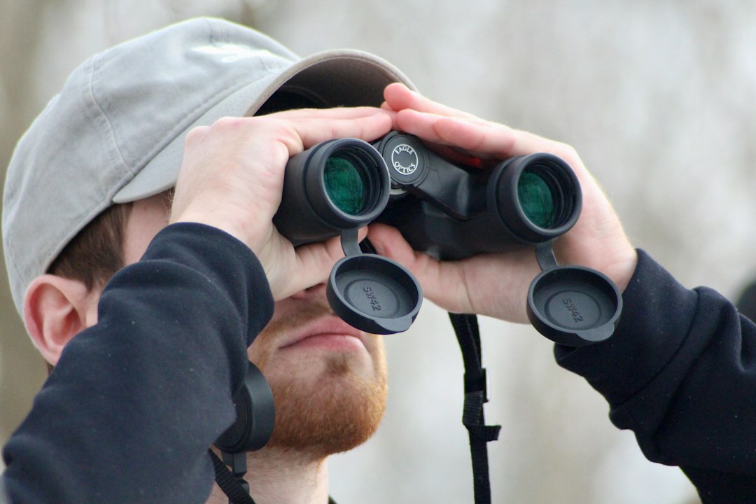 Birder observing wildlife outdoors with binoculars