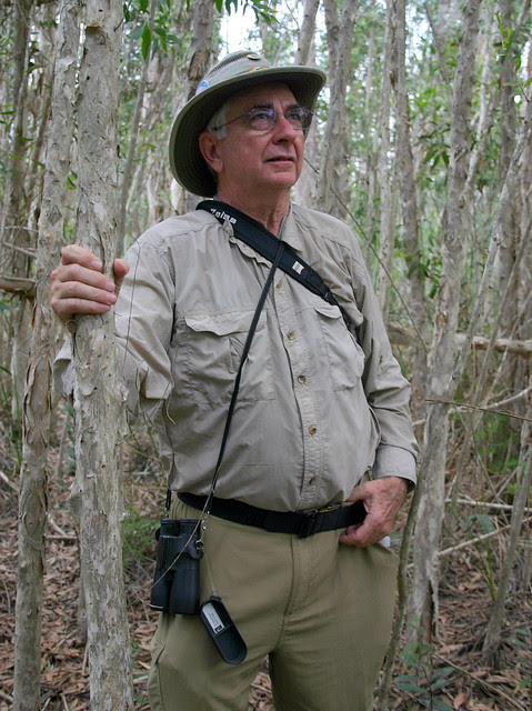 Dr. Kenneth Schneider in a South Florida woodland with binoculars